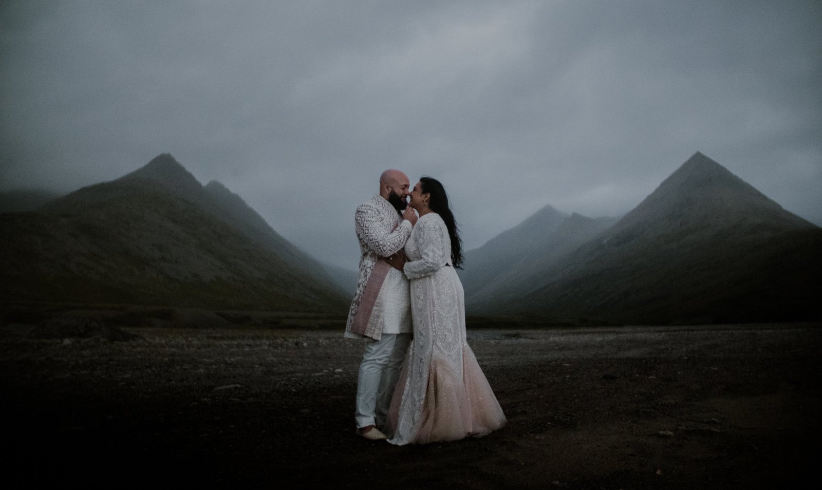 Hazra and Reggie nose to nose on black sand, misty peaks behind them in Stokksnes, Iceland